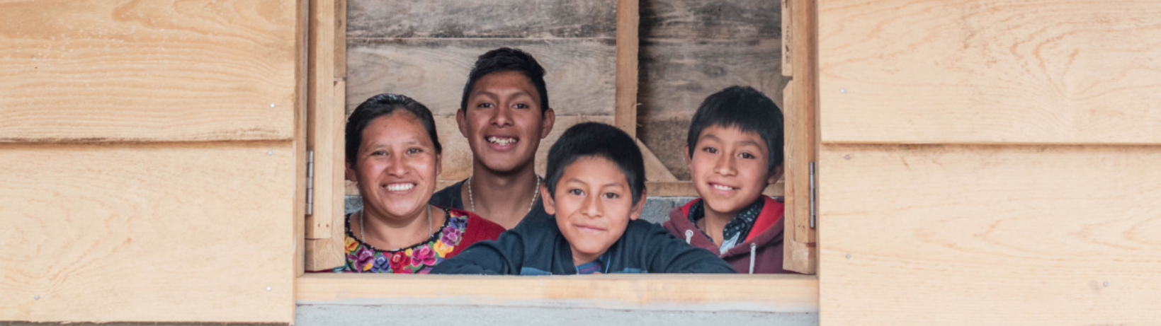 Familie in Guatemala kijkt door het raam van hun huis