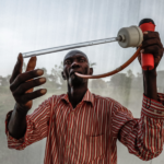 Evans Olang gebruikt een "Procopac mondaspirator" om muggen te vangen in de gecontroleerde omgeving van het Kenya Medical Research Institute (KEMRI) in Kisumu, Kenia.